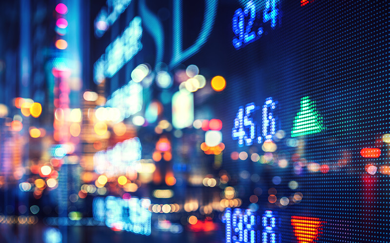 Collage of a city at night and a stock market ticker.